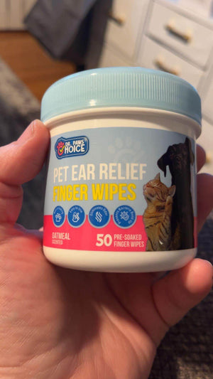 Container of pet ear relief finger wipes with oatmeal formula, designed for dogs and cats, held in hand, shown against a blurred background.